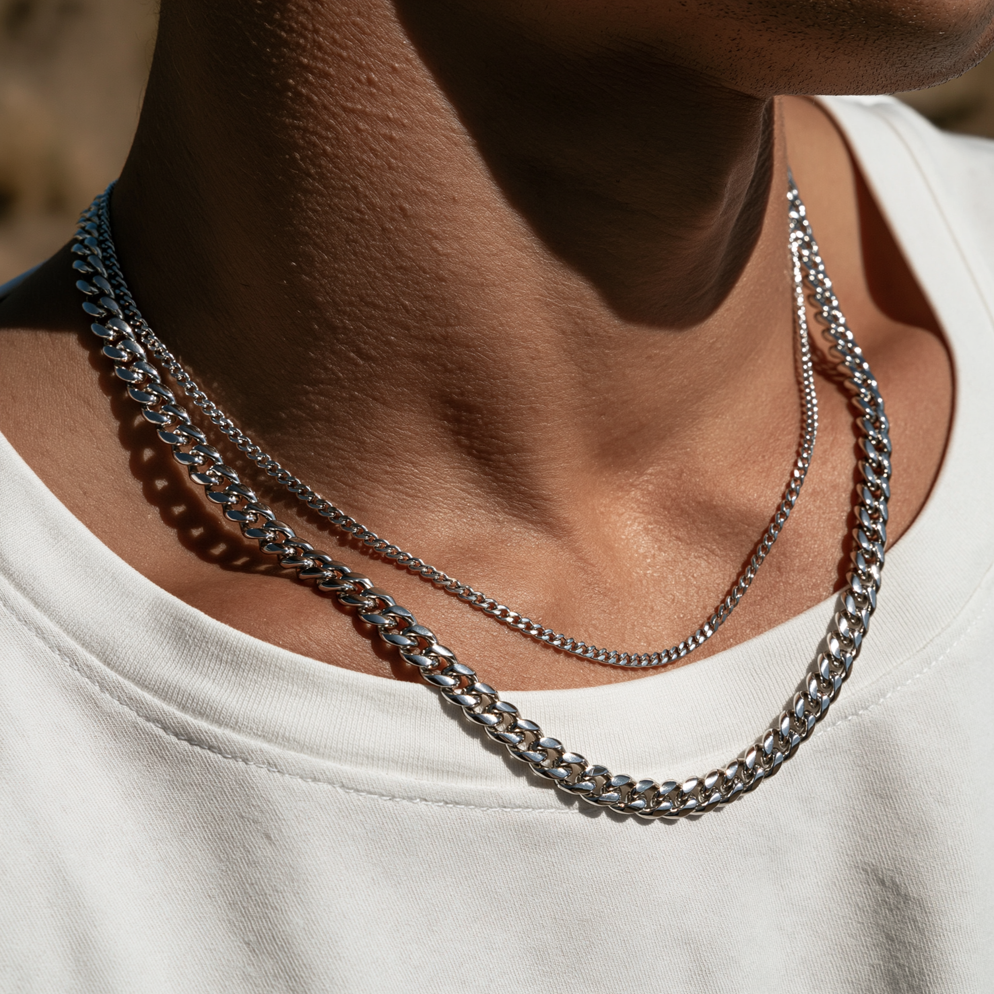 Gold chains layered on tan and white shirt